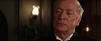 Movie still from “Batman Begins” (2005), directed by Christopher Nolan – An older man wearing a tuxedo looking at the camera; Close Up shot, Over the shoulder angle