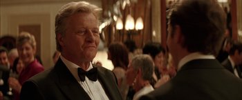 Movie still from “Batman Begins” (2005), directed by Christopher Nolan – An older man wearing a tuxedo and a black bow tie; Close Up shot, Over the shoulder angle