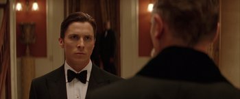 Movie still from “Batman Begins” (2005), directed by Christopher Nolan – A man in a tuxedo looking at himself in the mirror; Close Up shot, Over the shoulder angle