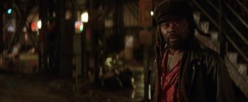 Movie still from “Batman Begins” (2005), directed by Christopher Nolan – A man with dreads standing in a dark room; Close Up shot, Low angle