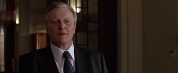 Movie still from “Batman Begins” (2005), directed by Christopher Nolan – An older man wearing a suit and tie; Close Up shot, Low angle