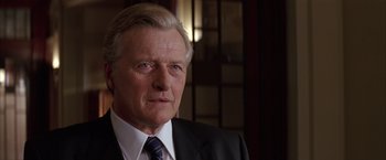 Movie still from “Batman Begins” (2005), directed by Christopher Nolan – An older man wearing a suit and tie; Close Up shot, Low angle