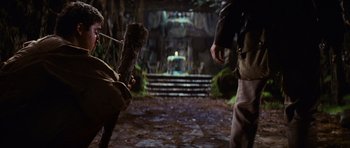 Movie still from “Raiders of the Lost Ark” (1981), directed by Steven Spielberg – Two people are walking down a path in the woods; Wide shot, Low angle