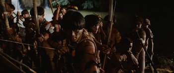 Movie still from “Raiders of the Lost Ark” (1981), directed by Steven Spielberg – A group of young men holding bows and arrows in their hands; Medium shot, High angle