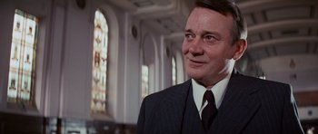 Movie still from “Raiders of the Lost Ark” (1981), directed by Steven Spielberg – A person wearing a suit and tie; Close Up shot, Low angle