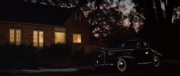 Movie still from “Raiders of the Lost Ark” (1981), directed by Steven Spielberg – An old car parked in front of a house at night; Extreme Wide shot, Low angle