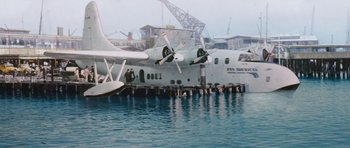 Movie still from “Raiders of the Lost Ark” (1981), directed by Steven Spielberg – An airplane sitting on top of a pier next to a body of water; Extreme Wide shot, Low angle