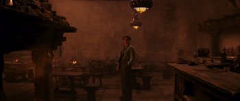 Movie still from “Raiders of the Lost Ark” (1981), directed by Steven Spielberg – A man standing in a room with lamps hanging from the ceiling; Wide shot, Low angle