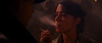 Movie still from “Raiders of the Lost Ark” (1981), directed by Steven Spielberg – A woman is smoking a cigarette while another woman looks on; Close Up shot, Over the shoulder angle