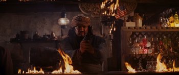 Movie still from “Raiders of the Lost Ark” (1981), directed by Steven Spielberg – A man holding a gun while standing in front of a fire pit; Medium shot, Low angle