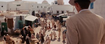 Movie still from “Raiders of the Lost Ark” (1981), directed by Steven Spielberg – A group of people walking down a street; Wide shot, Over the shoulder angle