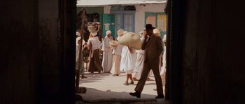 Movie still from “Raiders of the Lost Ark” (1981), directed by Steven Spielberg – A group of people walking down a street; Wide shot, Over the shoulder angle