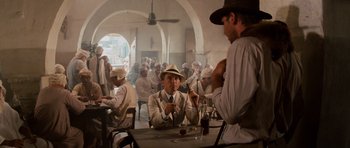 Movie still from “Raiders of the Lost Ark” (1981), directed by Steven Spielberg – A group of men sitting at a table in a room; Wide shot, Over the shoulder angle