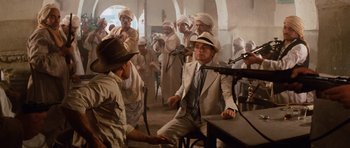 Movie still from “Raiders of the Lost Ark” (1981), directed by Steven Spielberg – A group of men in white suits and white hats; Wide shot, Over the shoulder angle