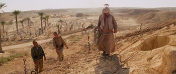 Movie still from “Raiders of the Lost Ark” (1981), directed by Steven Spielberg – A man walking on a dirt road with a camel; Wide shot, Low angle