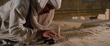 Movie still from “Raiders of the Lost Ark” (1981), directed by Steven Spielberg – A man wearing a white robe and a white head covering is holding a book; Medium shot, Low angle