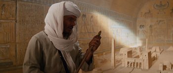 Movie still from “Raiders of the Lost Ark” (1981), directed by Steven Spielberg – A man in a turban is looking at his cell phone; Medium shot, Low angle