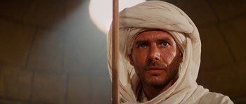 Movie still from “Raiders of the Lost Ark” (1981), directed by Steven Spielberg – A person wearing a head covering; Close Up shot, Over the shoulder angle