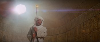 Movie still from “Raiders of the Lost Ark” (1981), directed by Steven Spielberg – A man in a white robe holding a spear; Medium shot, Low angle