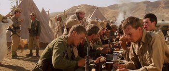 Movie still from “Raiders of the Lost Ark” (1981), directed by Steven Spielberg – A group of men sitting at a table eating food; Medium shot, High angle
