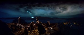 Movie still from “Raiders of the Lost Ark” (1981), directed by Steven Spielberg – A group of people standing around in the dark; Extreme Wide shot, High angle