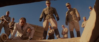 Movie still from “Raiders of the Lost Ark” (1981), directed by Steven Spielberg – A group of men standing next to each other on top of a hill; Wide shot, Low angle