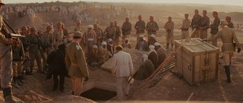 Movie still from “Raiders of the Lost Ark” (1981), directed by Steven Spielberg – A group of men standing in front of a hole in the ground; Wide shot, High angle