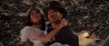 Movie still from “Raiders of the Lost Ark” (1981), directed by Steven Spielberg – A man and a woman are sitting on the ground; Medium shot, Low angle