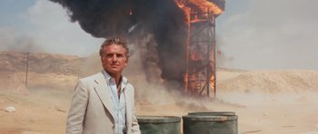Movie still from “Raiders of the Lost Ark” (1981), directed by Steven Spielberg – A man standing in front of an oil rig on fire; Medium shot, Low angle