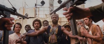 Movie still from “Raiders of the Lost Ark” (1981), directed by Steven Spielberg – A group of men standing next to each other holding guns; Medium shot, Low angle