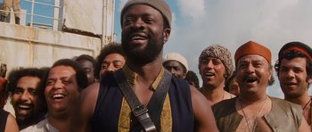 Movie still from “Raiders of the Lost Ark” (1981), directed by Steven Spielberg – A group of men standing next to each other on a street; Medium shot, Low angle