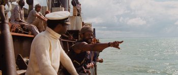 Movie still from “Raiders of the Lost Ark” (1981), directed by Steven Spielberg – A man in a sailor's hat points to the sky; Medium shot, Low angle