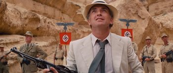 Movie still from “Raiders of the Lost Ark” (1981), directed by Steven Spielberg – A man in a suit and a hat looking up at the sky; Medium shot, Low angle