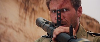 Movie still from “Raiders of the Lost Ark” (1981), directed by Steven Spielberg – A man holding a gun in his mouth; Close Up shot, Over the shoulder angle