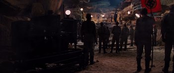 Movie still from “Raiders of the Lost Ark” (1981), directed by Steven Spielberg – A group of people standing in a cave; Wide shot, High angle
