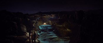 Movie still from “Raiders of the Lost Ark” (1981), directed by Steven Spielberg – A light is on in the middle of a cave; Extreme Wide shot, High angle