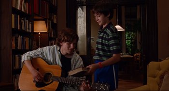 Movie still from “The Squid and the Whale” (2005), directed by Noah Baumbach – Two young men are playing a guitar and a book; Medium shot, Over the shoulder angle