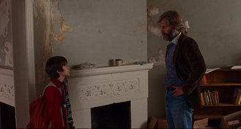 Movie still from “The Squid and the Whale” (2005), directed by Noah Baumbach – A man and a boy standing in front of a fire place; Medium shot, Over the shoulder angle