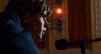 Movie still from “The Squid and the Whale” (2005), directed by Noah Baumbach – A young man is speaking into a microphone in front of an orange light; Close Up shot, Low angle