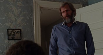 Movie still from “The Squid and the Whale” (2005), directed by Noah Baumbach – A man with a beard and a blue shirt is standing in front of a door; Medium shot, Over the shoulder angle