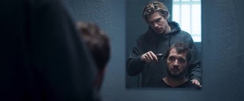 A man is looking at himself in the mirror while shaving