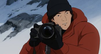 Movie still from “The Summit of the Gods” (2021), directed by Patrick Imbert – A man holding a camera while standing in the snow; Extreme Close Up shot, High angle
