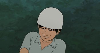 Movie still from “The Summit of the Gods” (2021), directed by Patrick Imbert – A man wearing a white helmet is looking down; Close Up shot, High angle