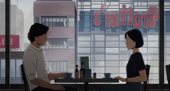 Movie still from “The Summit of the Gods” (2021), directed by Patrick Imbert – Two people are sitting at a table in front of a building; Wide shot, Over the shoulder angle