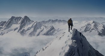 Movie still from “The Summit of the Gods” (2021), directed by Patrick Imbert – A man standing on top of a snow covered mountain; Extreme Wide shot, Low angle