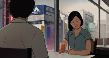 Movie still from “The Summit of the Gods” (2021), directed by Patrick Imbert – A woman sitting at a table with a glass of orange juice; Medium shot, Over the shoulder angle