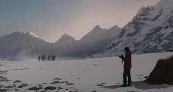 Movie still from “The Summit of the Gods” (2021), directed by Patrick Imbert – A person standing in the snow with a camera; Extreme Wide shot, Low angle
