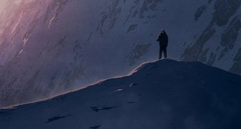 Movie still from “The Summit of the Gods” (2021), directed by Patrick Imbert – A man standing on top of a snow covered slope; Extreme Wide shot, Low angle