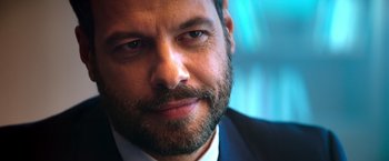 Movie still from “The Takedown” (2022), directed by Louis Leterrier – A man with a beard and mustache; Close Up shot, Over the shoulder angle