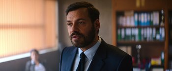 Movie still from “The Takedown” (2022), directed by Louis Leterrier – A person wearing a suit and tie; Close Up shot, Over the shoulder angle